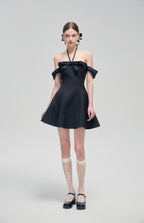Nero Ritratto Off-Shoulder Dress in black with A-line silhouette, double off-shoulder straps, and halter neckline, styled with sheer socks and black heels.