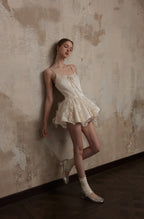 Model leaning against wall in Nuvola Mousse Sun Dress, emphasizing its dreamy, lightweight fabric and flowing ruffle details.